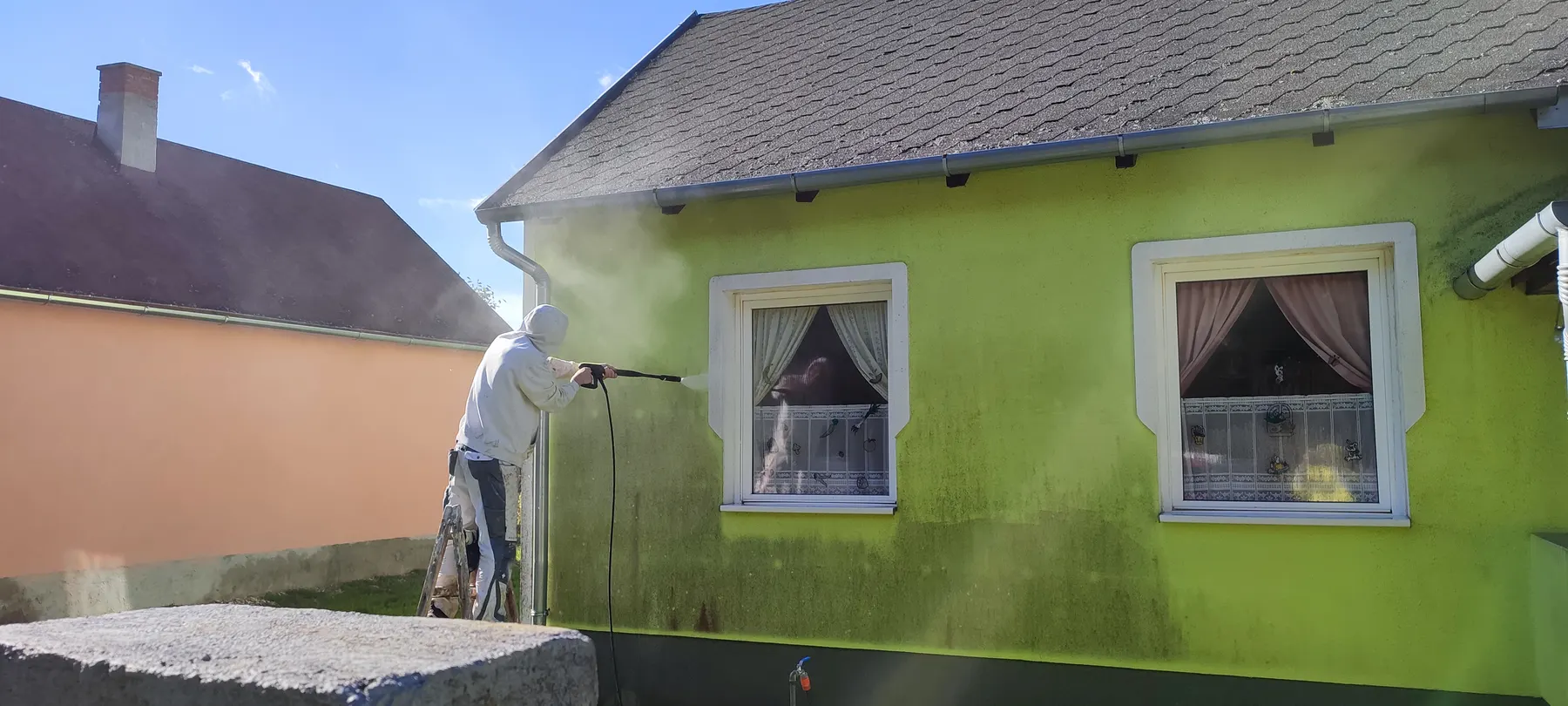 Zöld homlokzat nyomásmosás közben, felújítás előtt