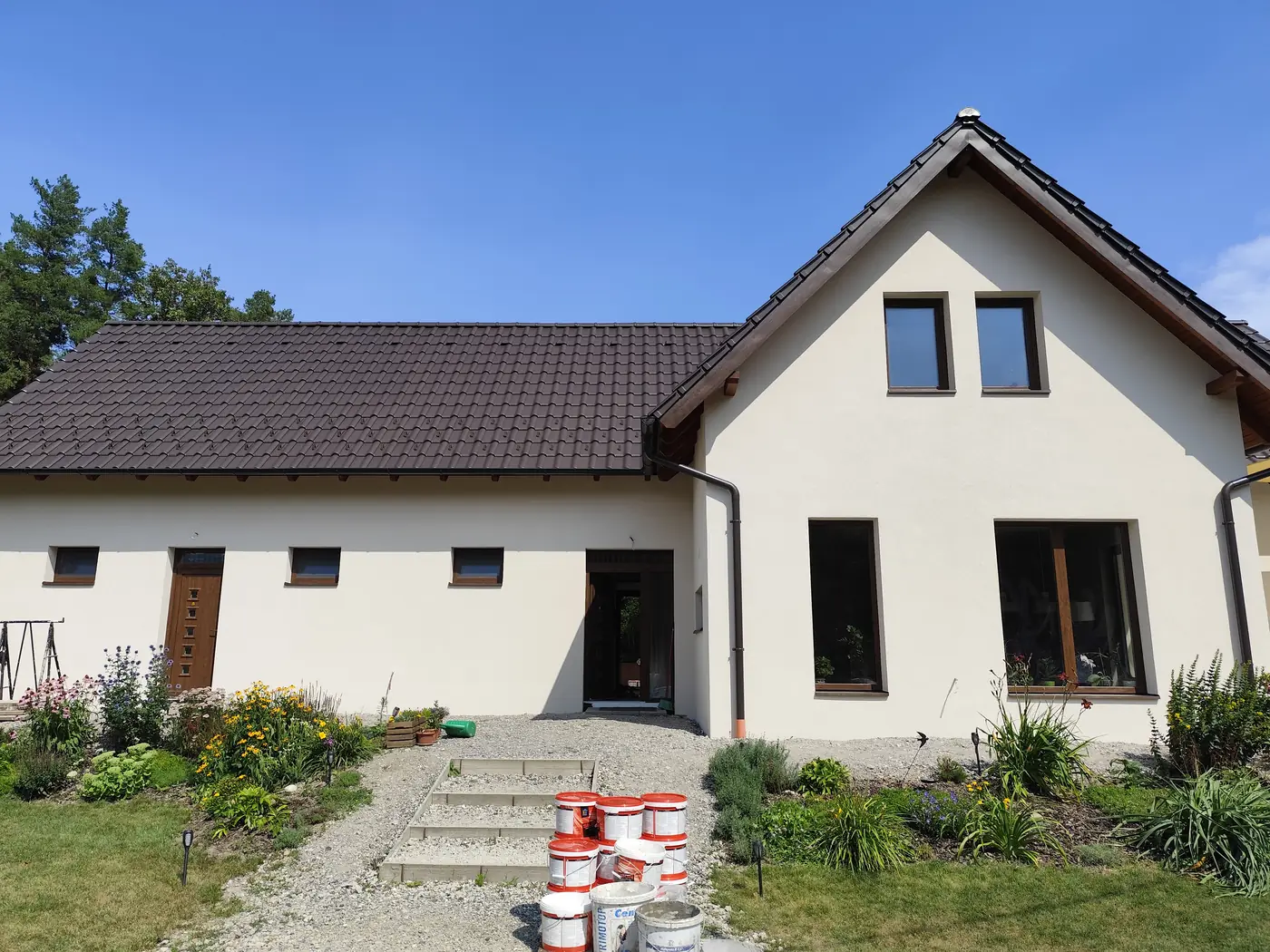 Elkészült, krémszínű homlokzat sötét tetővel és kerttel
